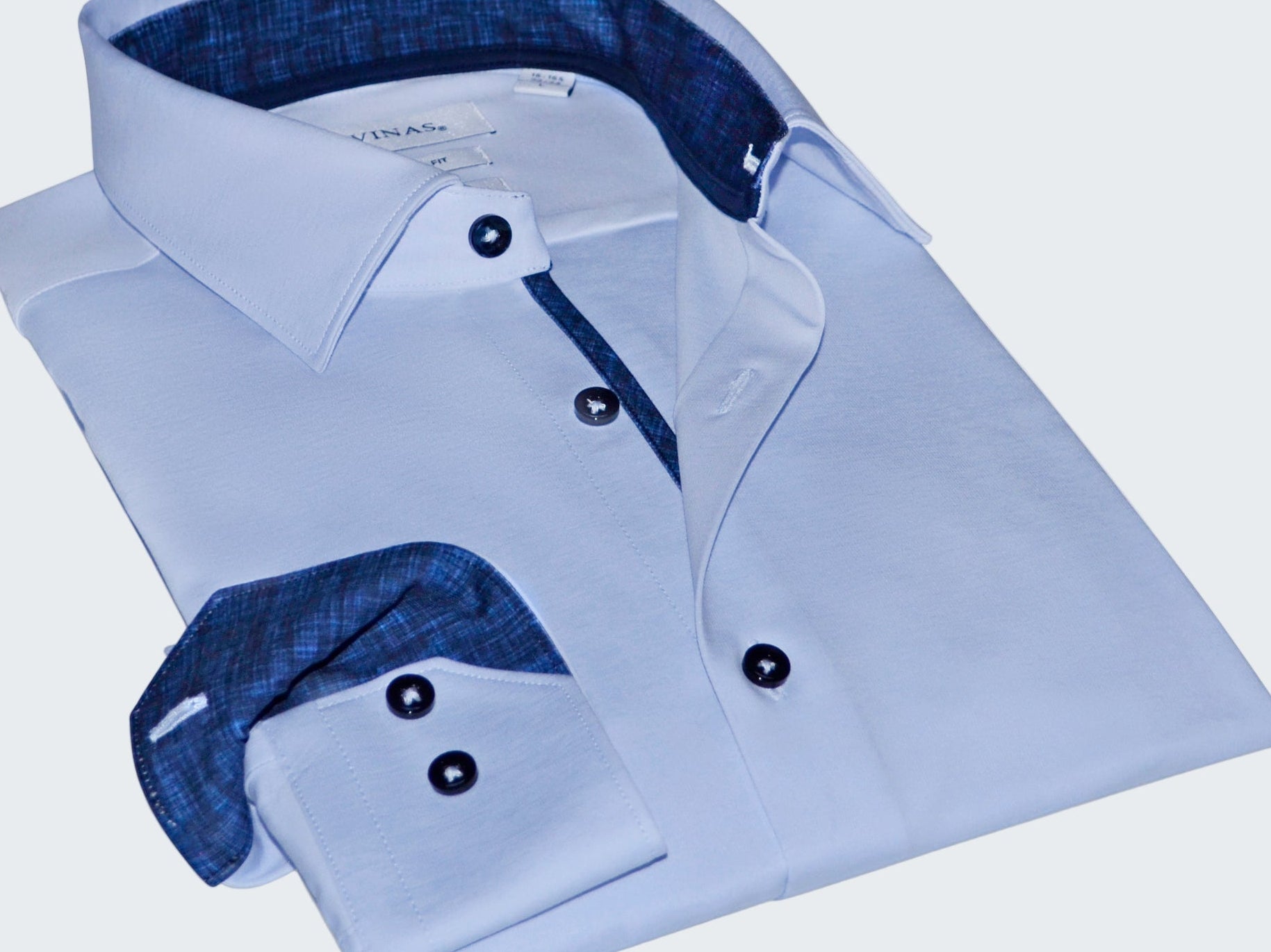 Folded light blue dress shirt with dark blue interior on a white background