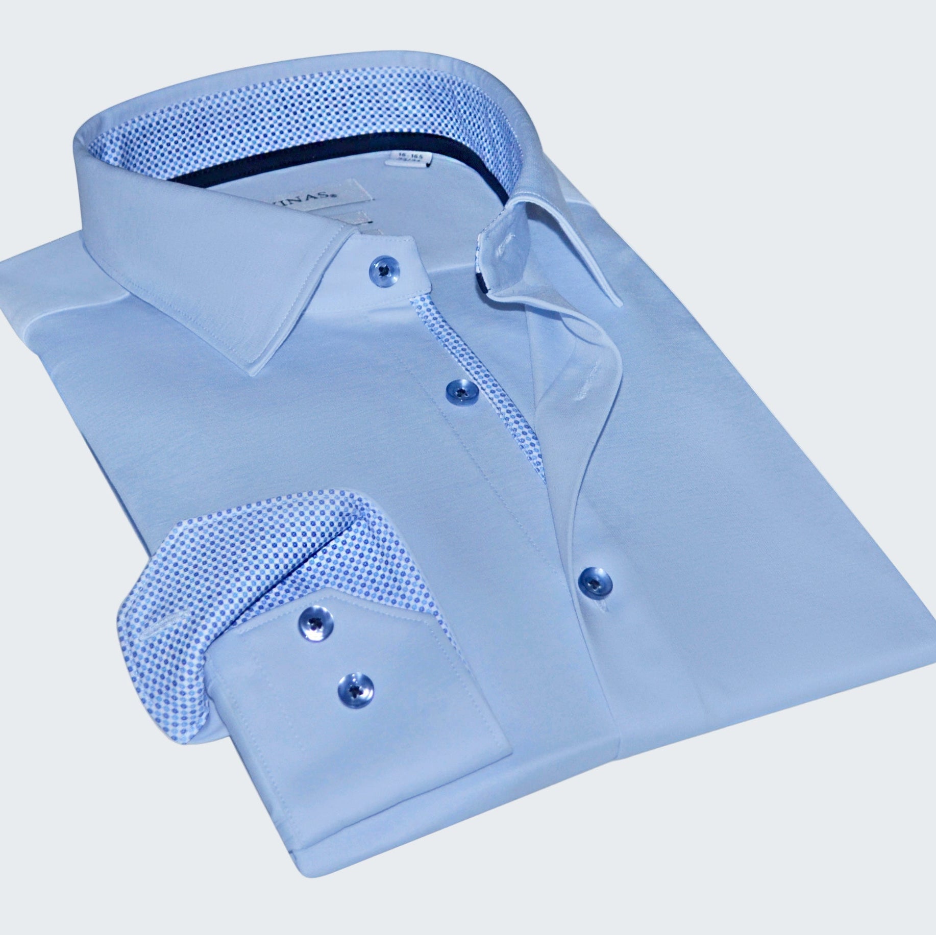 Folded light blue dress shirt with textured collar and cuffs on a white background