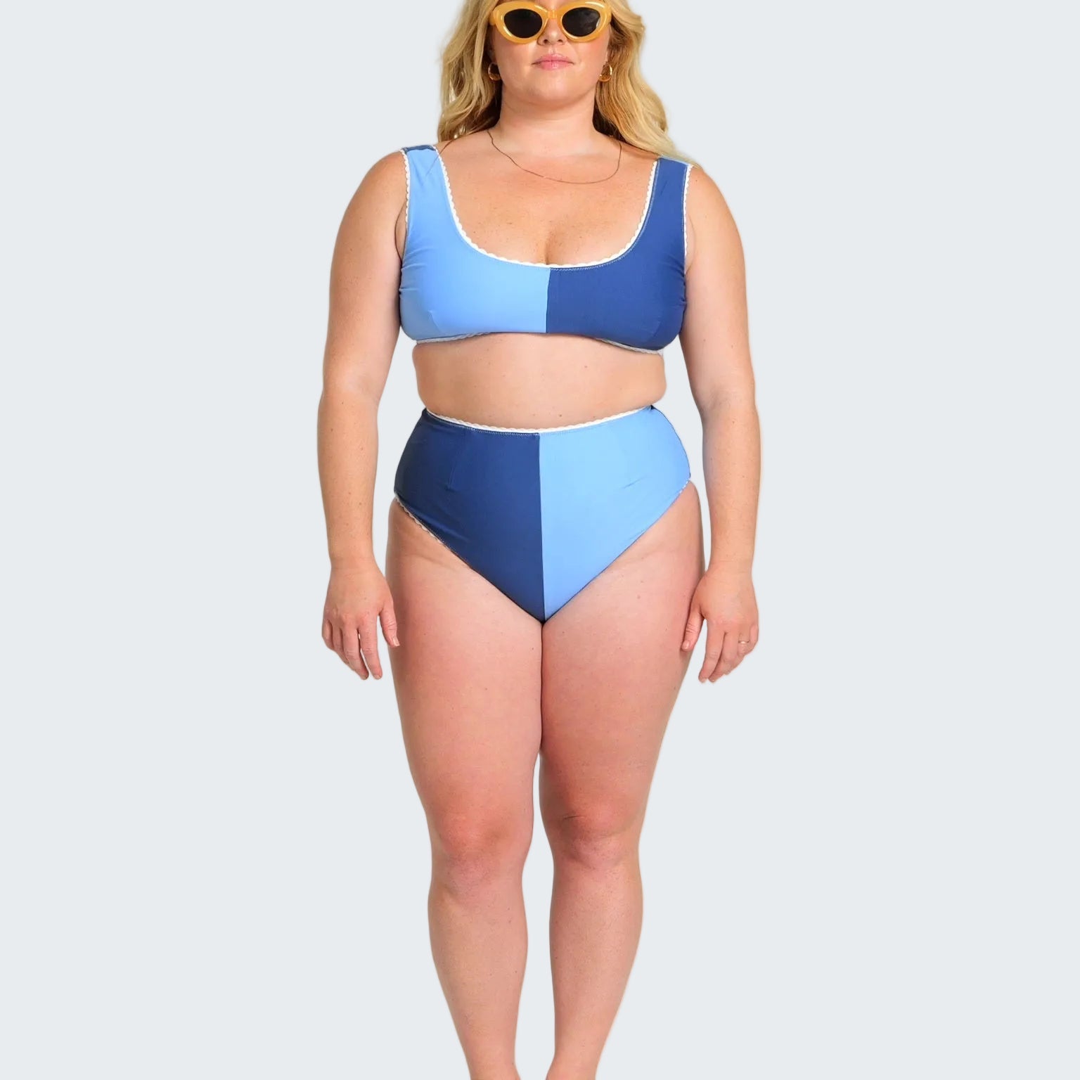 Woman wearing a blue and navy two-piece swimsuit on a white background