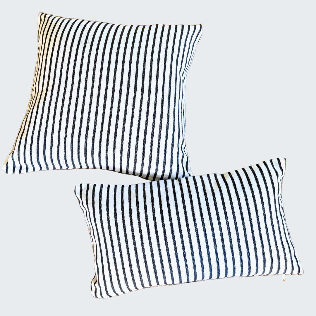 Two black and white striped pillows on a woven mat.