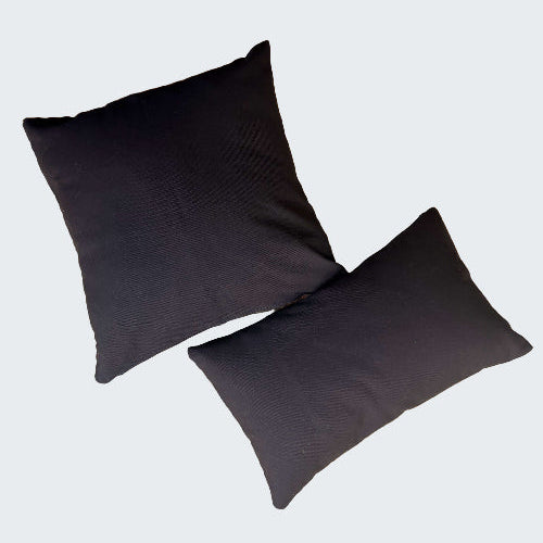 Two black pillows on a textured beige surface