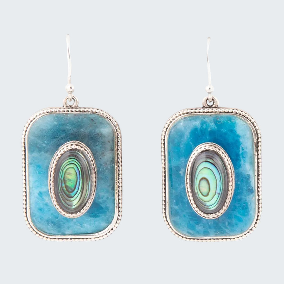 Pair of earrings with blue square frames and greenish-center stones on a white background