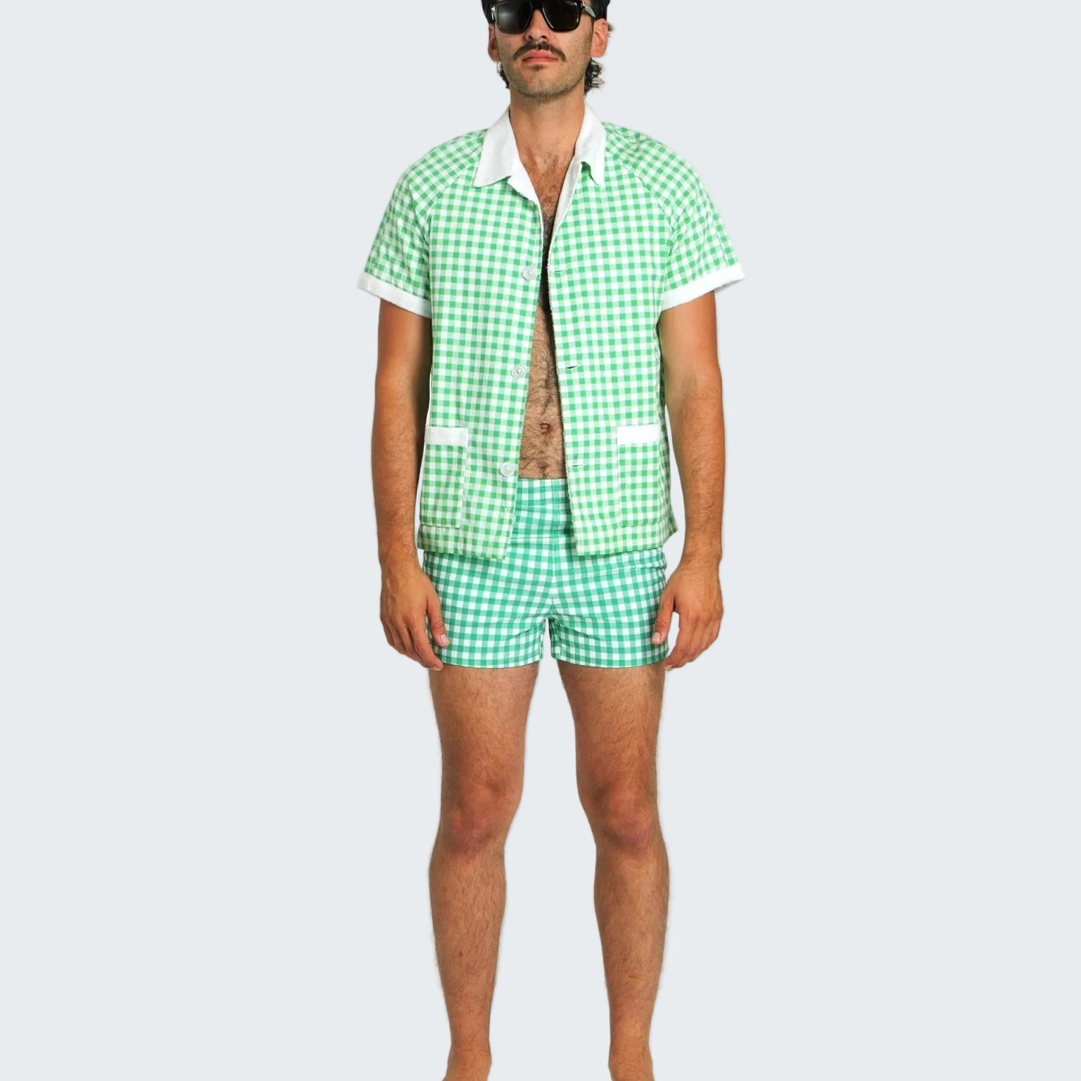 Man wearing a green checkered shirt and shorts set on a white background