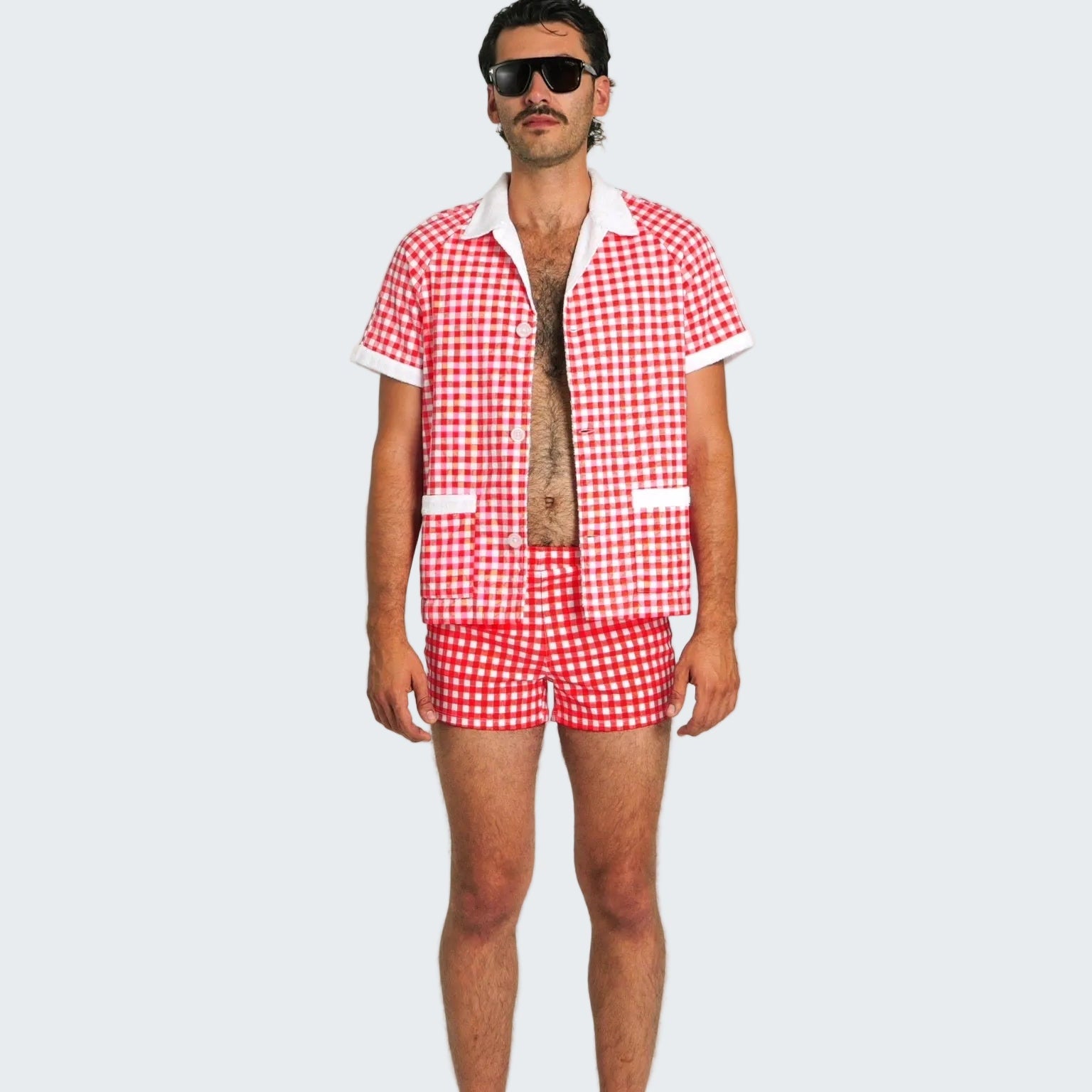 Man wearing a red and white checkered shirt and shorts on a white background