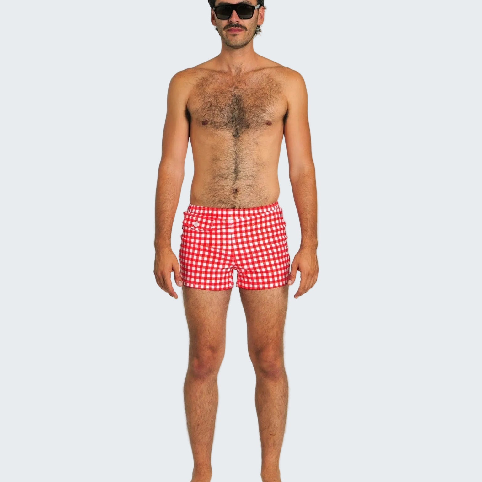 Man wearing red checkered swim shorts on a white background