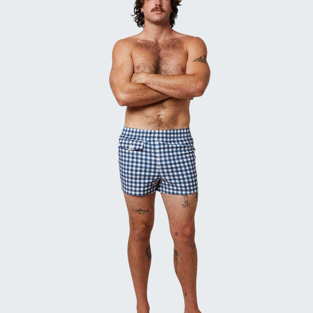 Man wearing blue checkered swim shorts on a white background