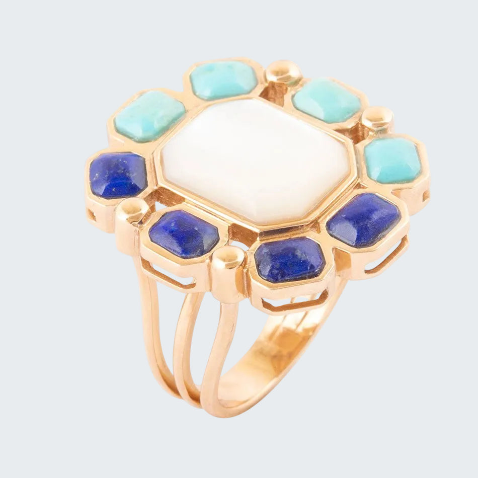 Gold ring with central white stone surrounded by blue and green stones on a white background