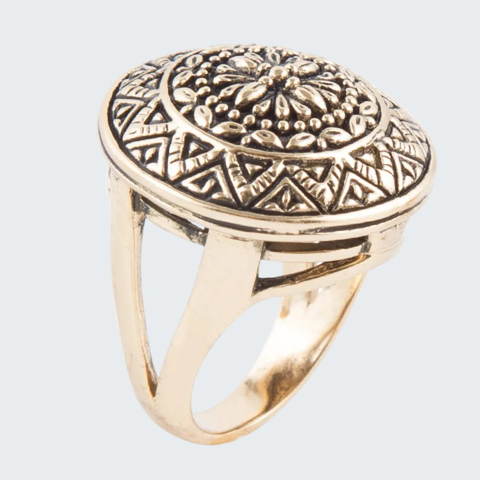 Gold ring with intricate design on a white background