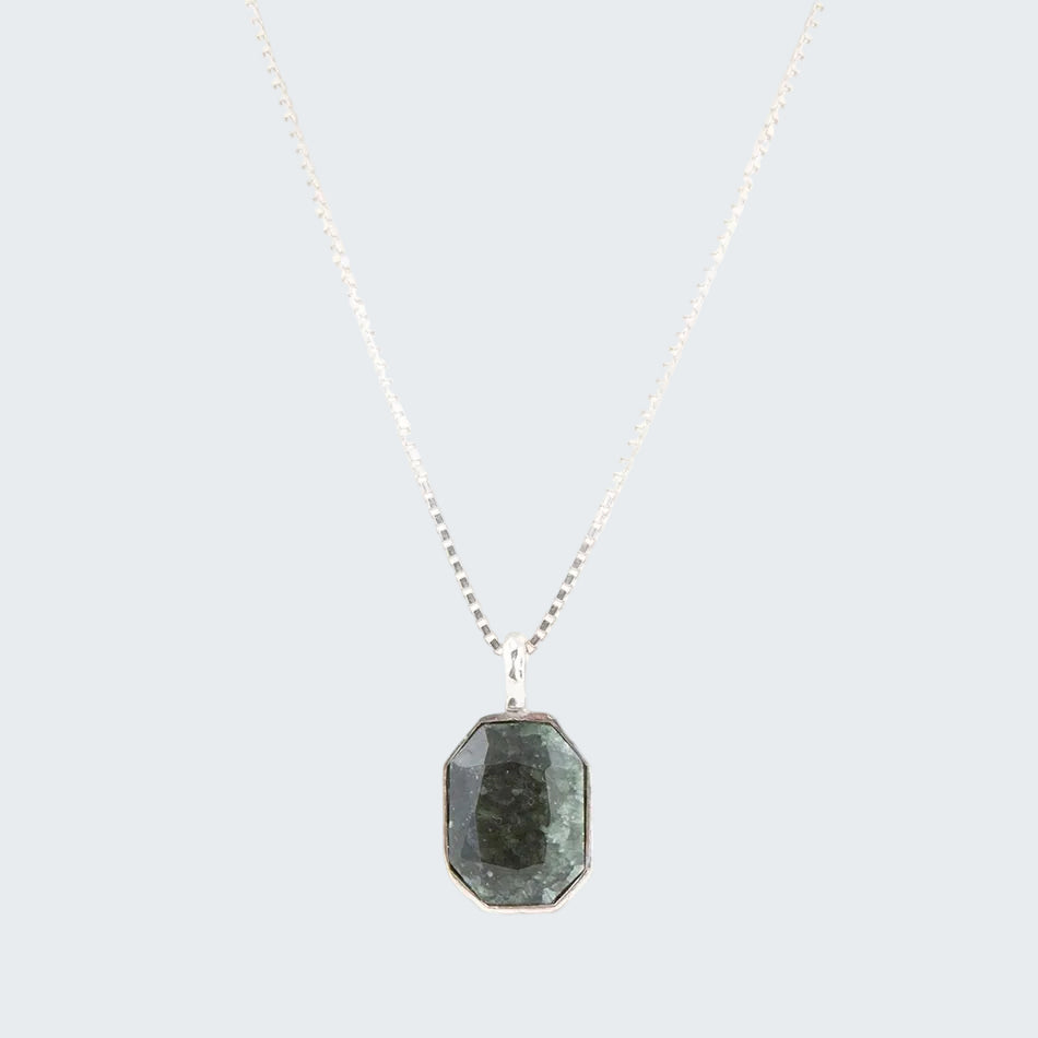 Necklace with a green gemstone pendant on a white background