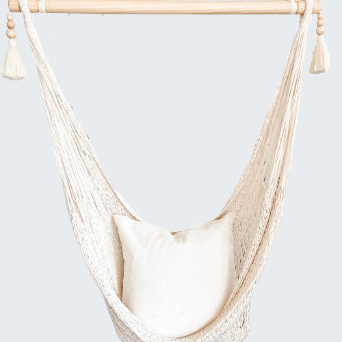 White hammock chair with a pillow in a room with decorative elements.