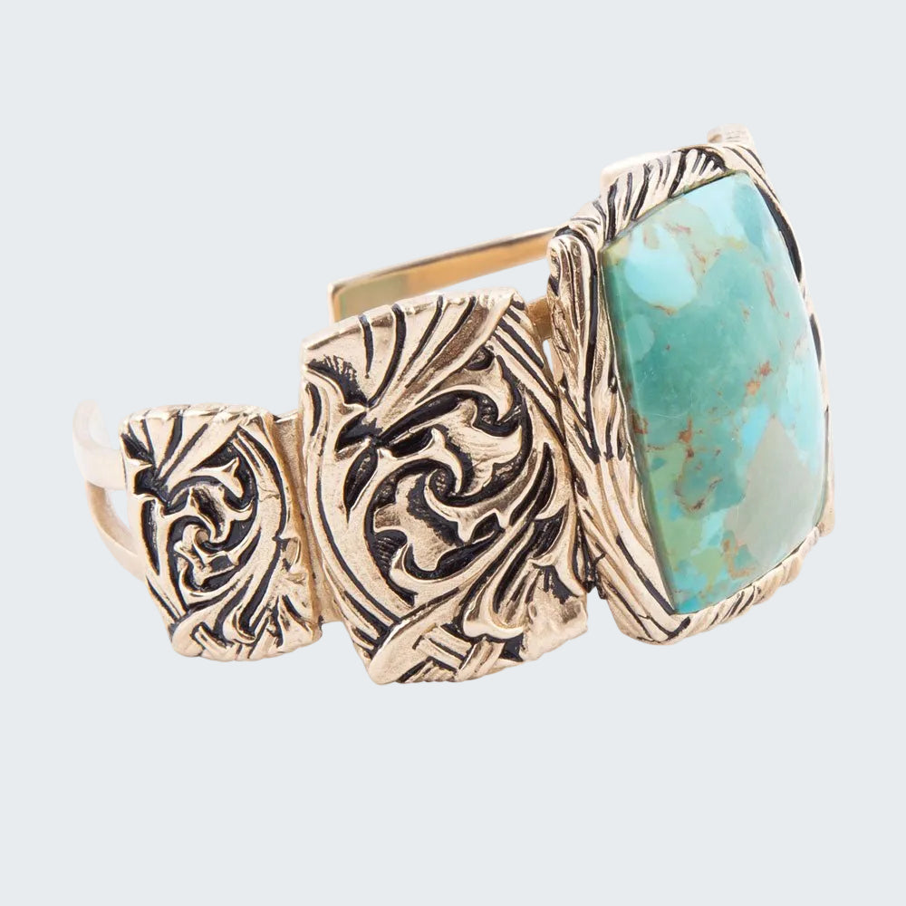 Gold and turquoise ring with intricate design on a white background