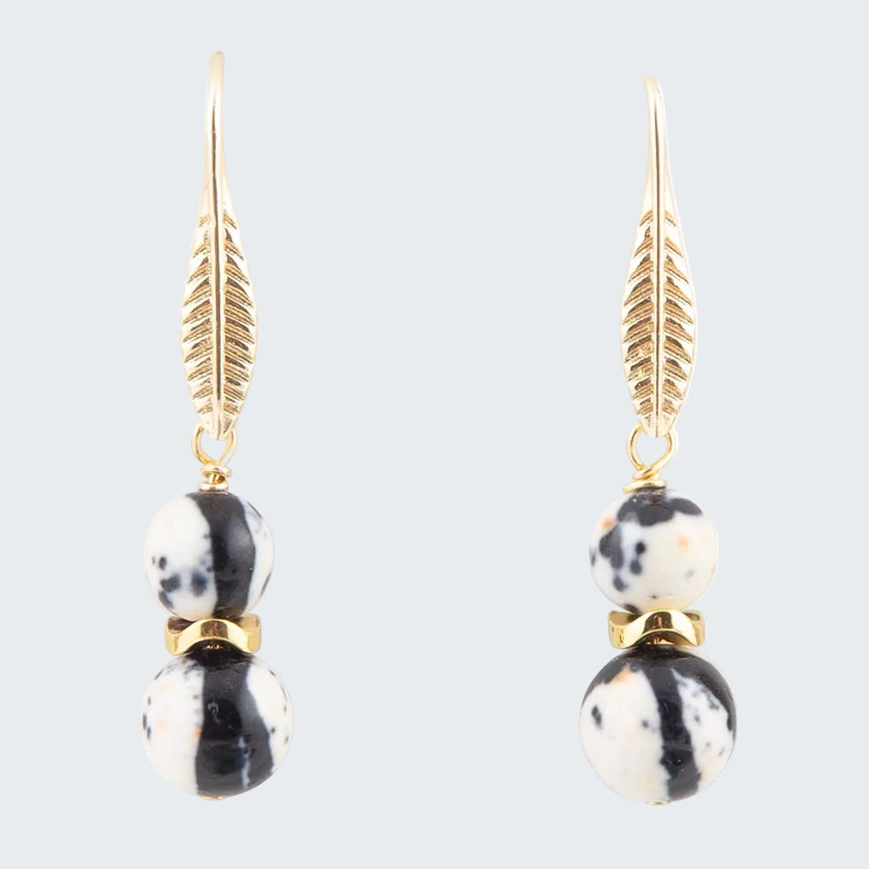 Pair of earrings with gold feather accents and black and white bead designs on a white background