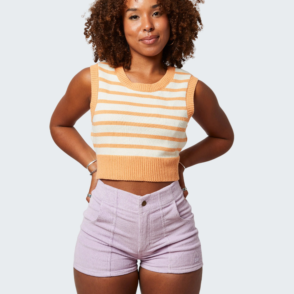 Woman wearing a striped sleeveless top and high-waisted shorts on a white background