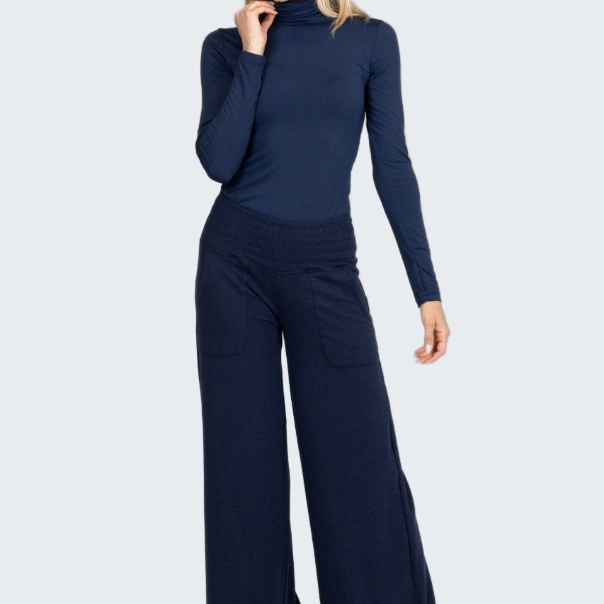 Woman wearing a navy blue turtleneck and wide-leg pants on a white background