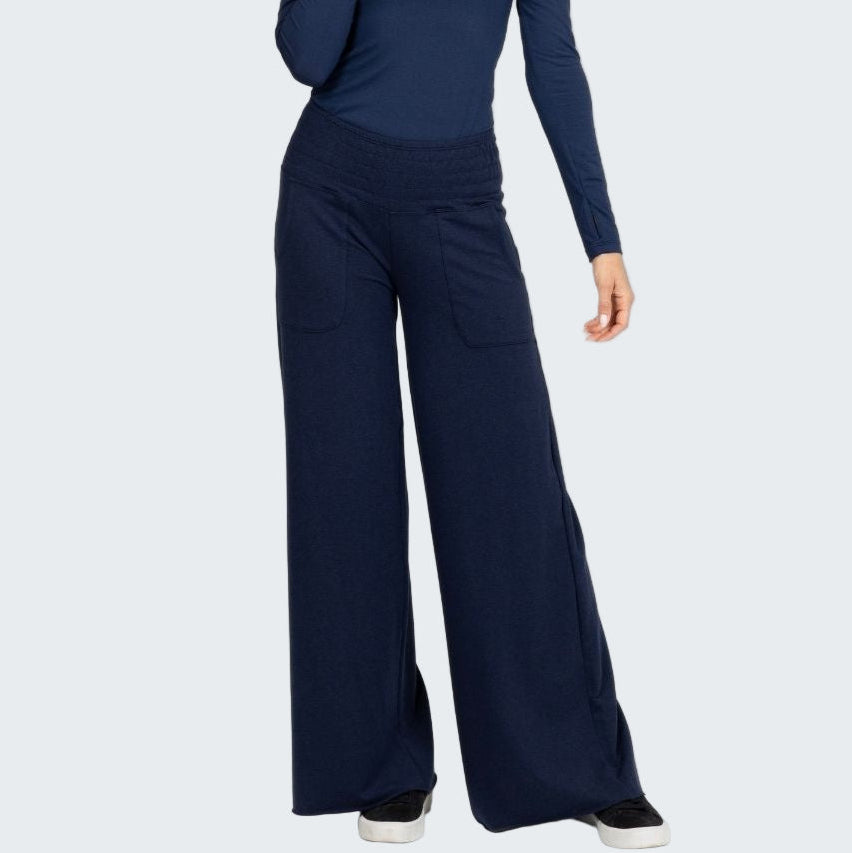 Woman wearing a navy blue turtleneck and wide-leg pants on a white background