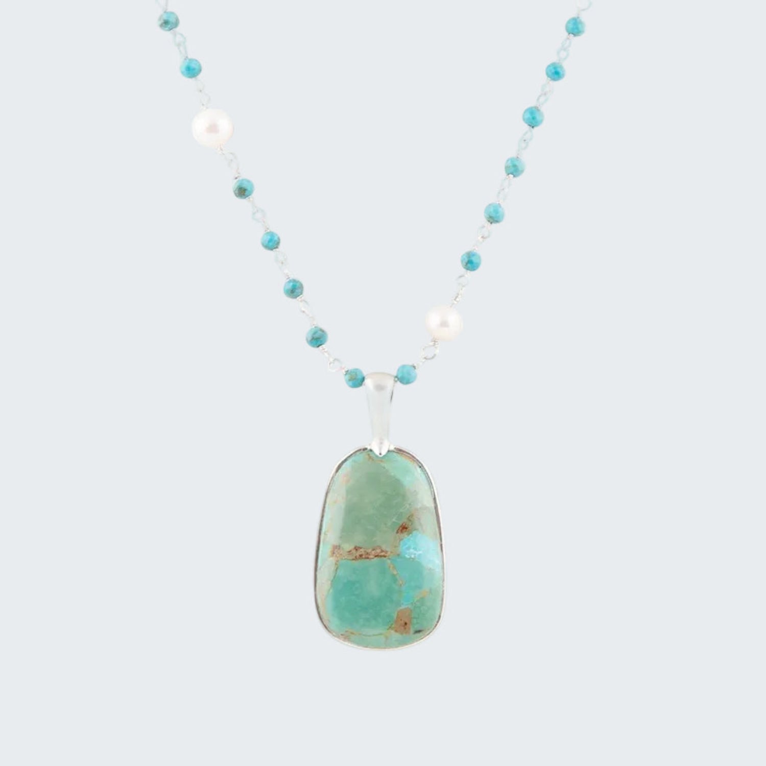 Necklace with a turquoise pendant and white pearls on a white background