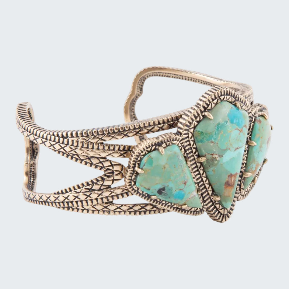 Turquoise stone cuff bracelet with intricate metalwork on a white background