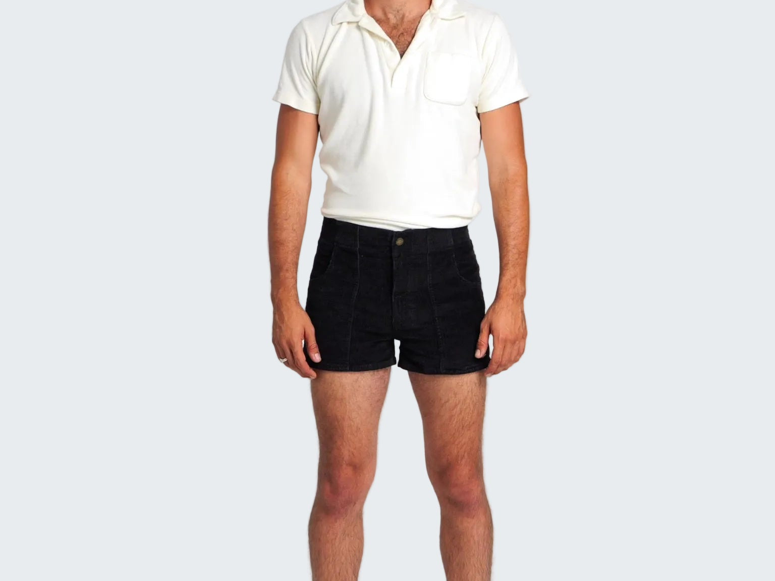 Man wearing a white polo shirt, black shorts, and striped socks on a plain background