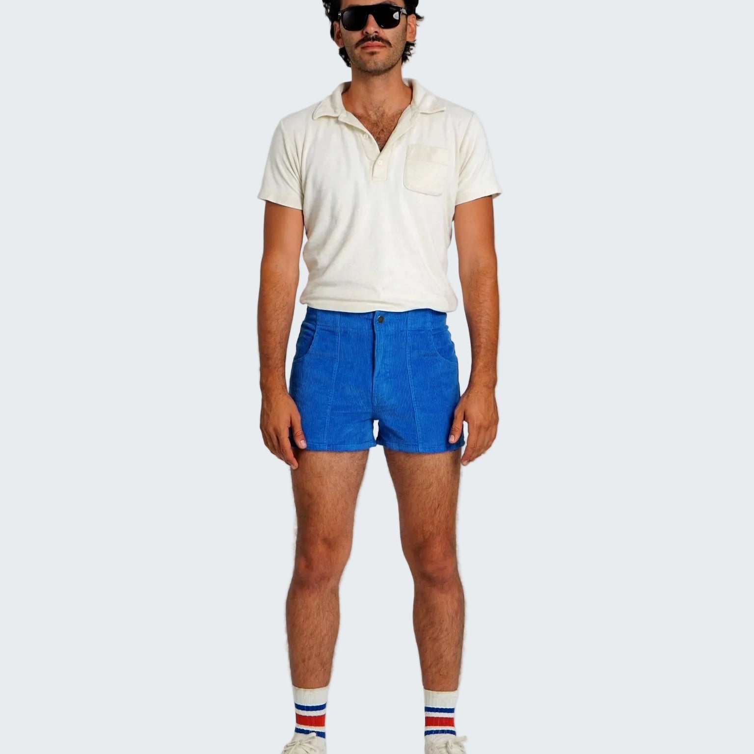 Man wearing a white shirt, blue shorts, and striped socks on a plain background
