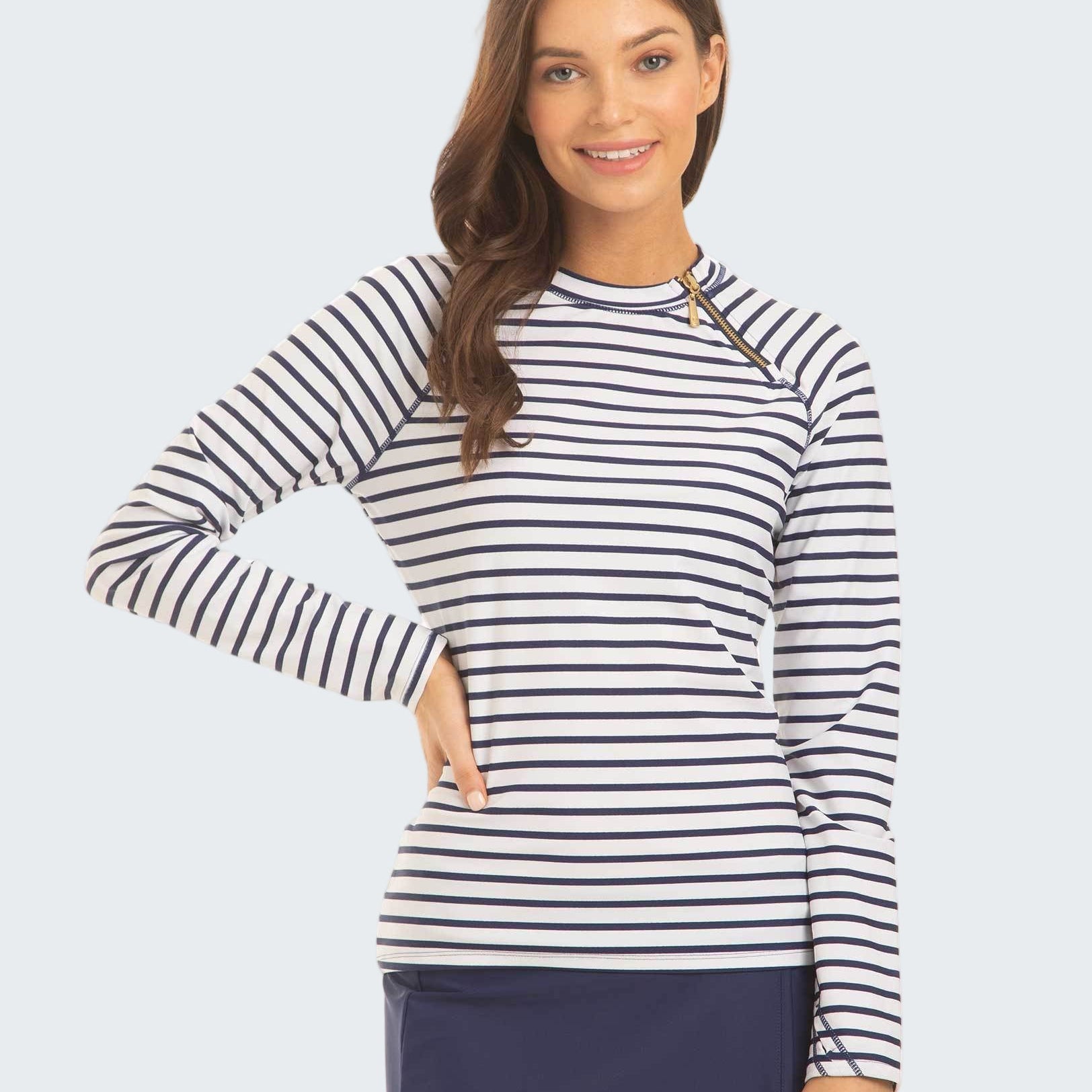 Woman wearing a striped long-sleeve top and navy skirt on a white background