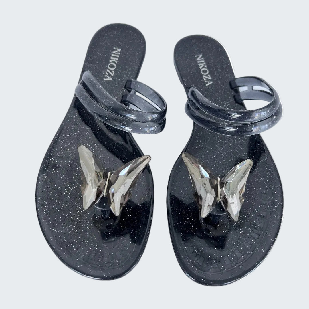 Black sandals with butterfly designs on a white background