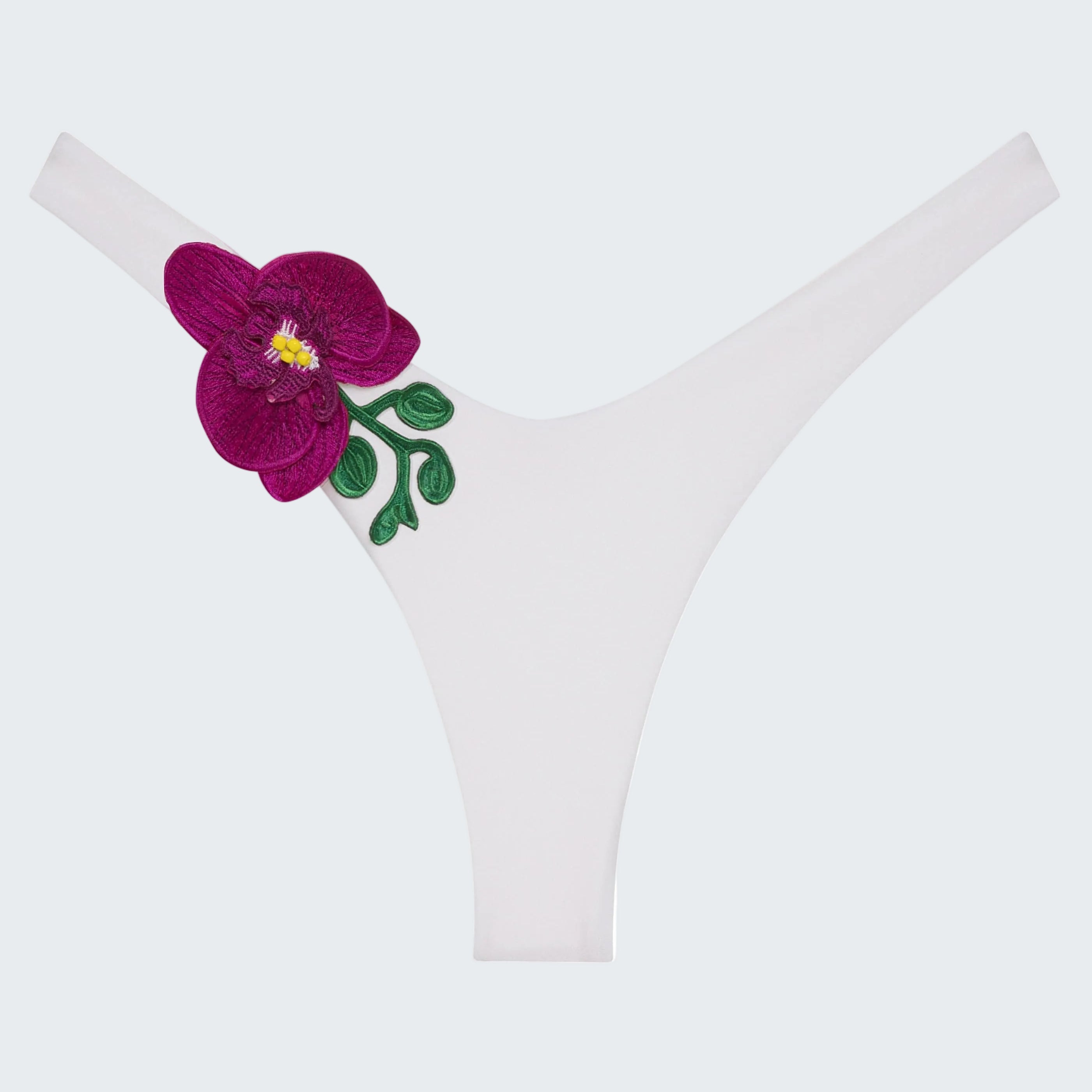 White thong underwear featuring a prominent embroidered magenta orchid flower with green leaves and a yellow center on the left side.