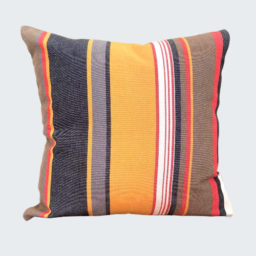 Striped pillow with multicolor pattern on a wooden stool against a plain background