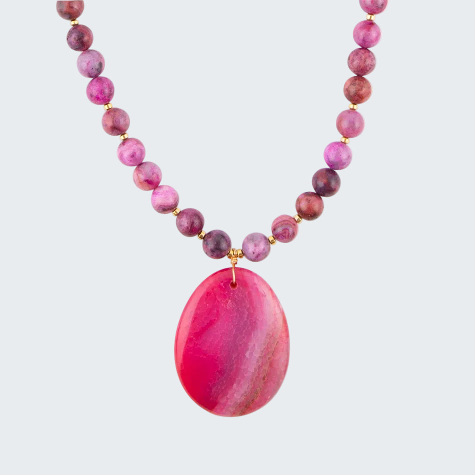Necklace with pink and purple beads and a large pink pendant on a white background