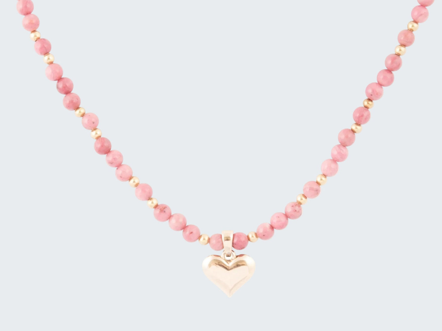 Necklace with pink beads and a heart-shaped pendant on a white background
