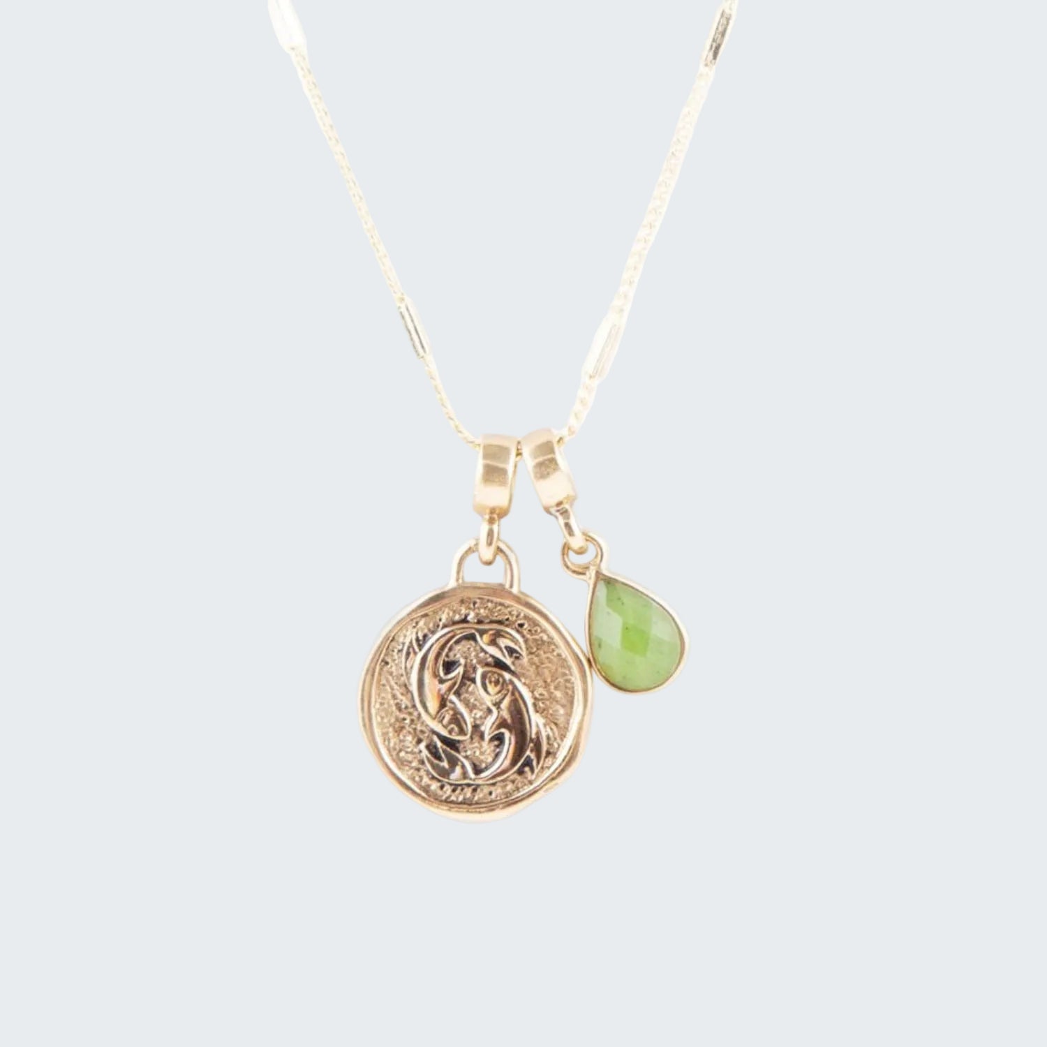 Gold necklace with a green pendant on a white background