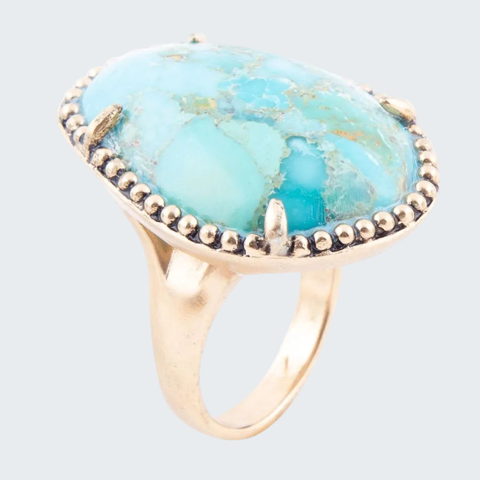 Ring with a large turquoise stone and gold accents on a white background