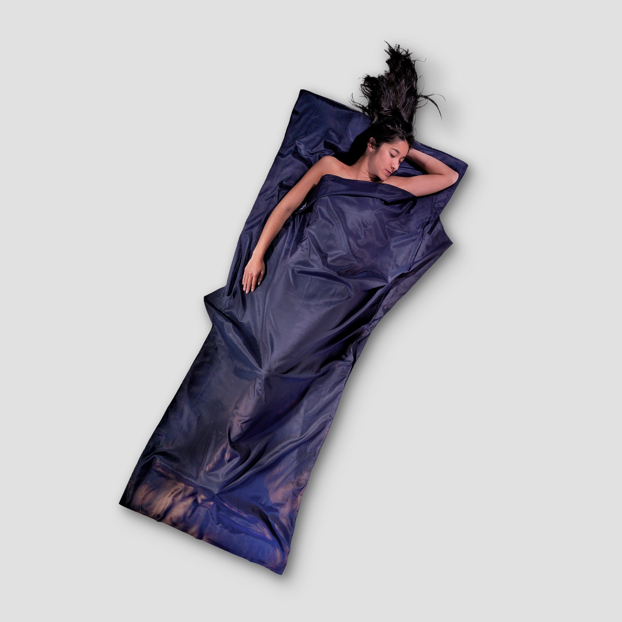 Person lying on a purple satin sheet against a light gray background