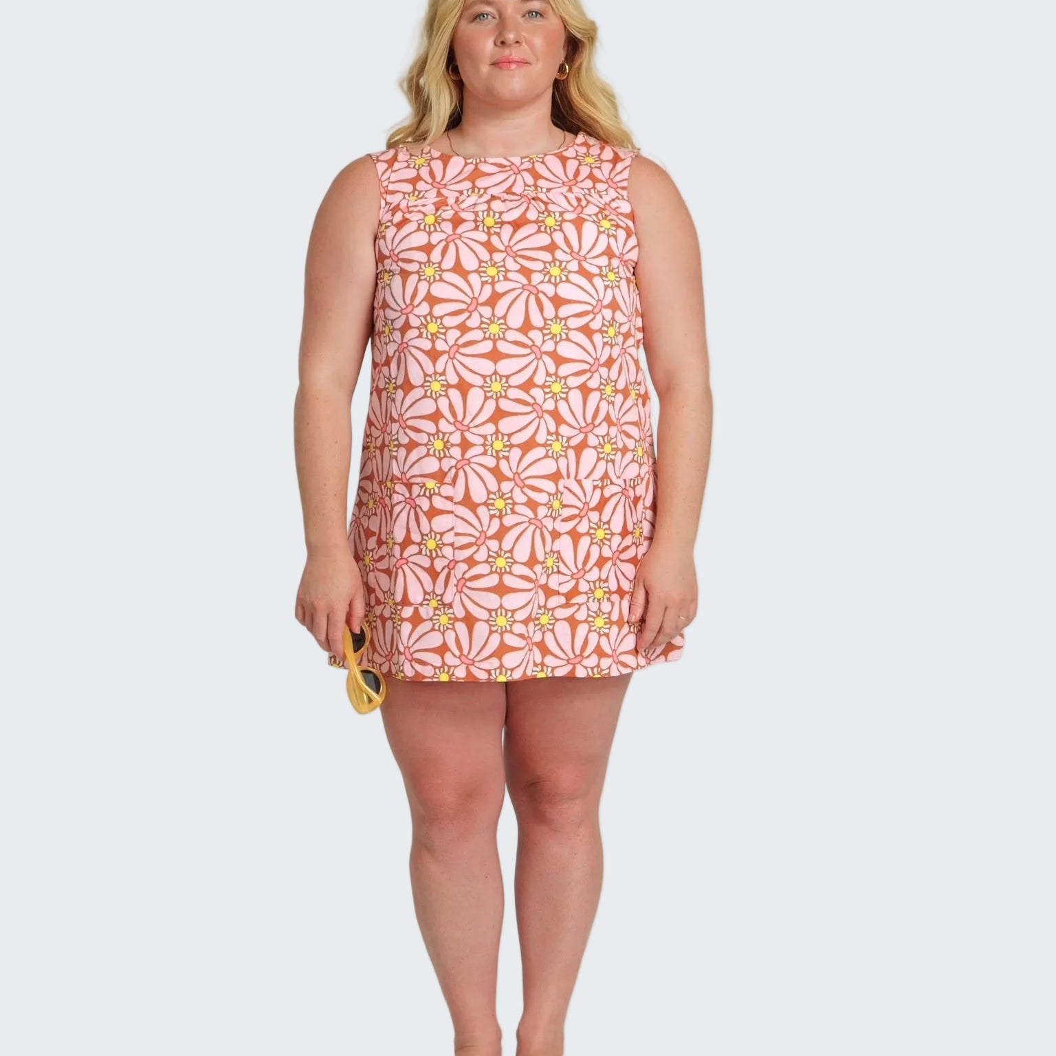 Woman wearing a sleeveless dress with a floral pattern on a white background