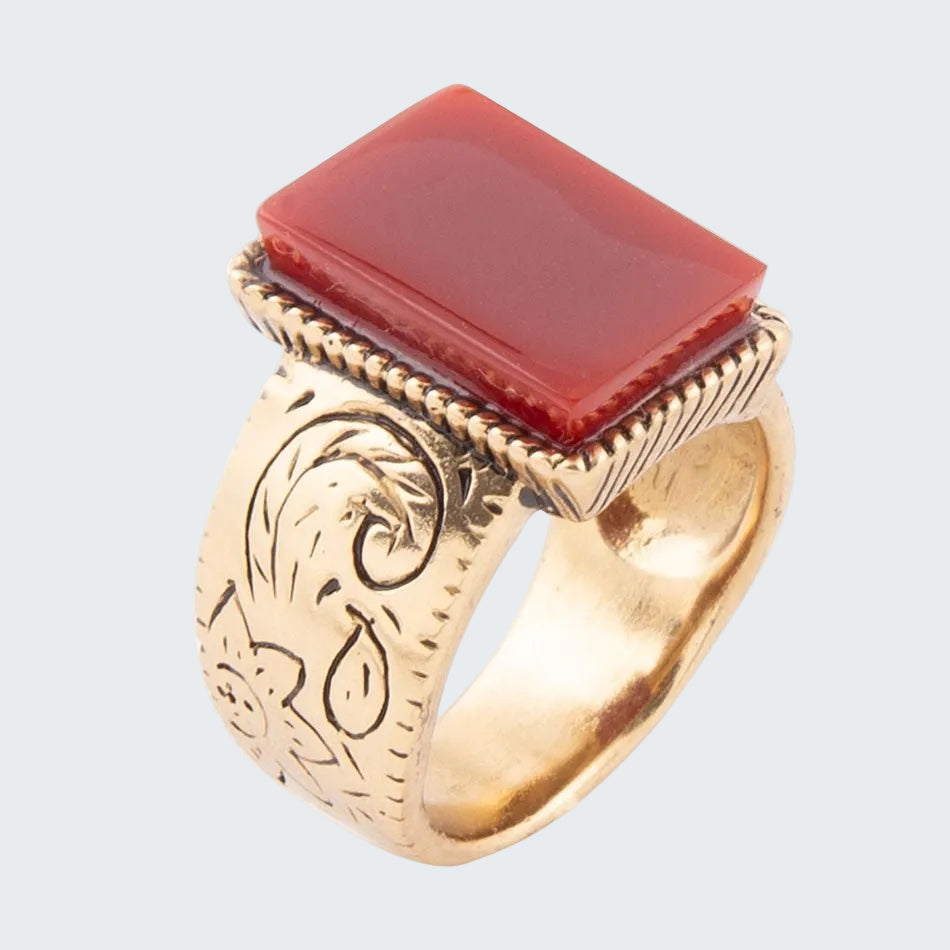Gold ring with a red stone on a white background