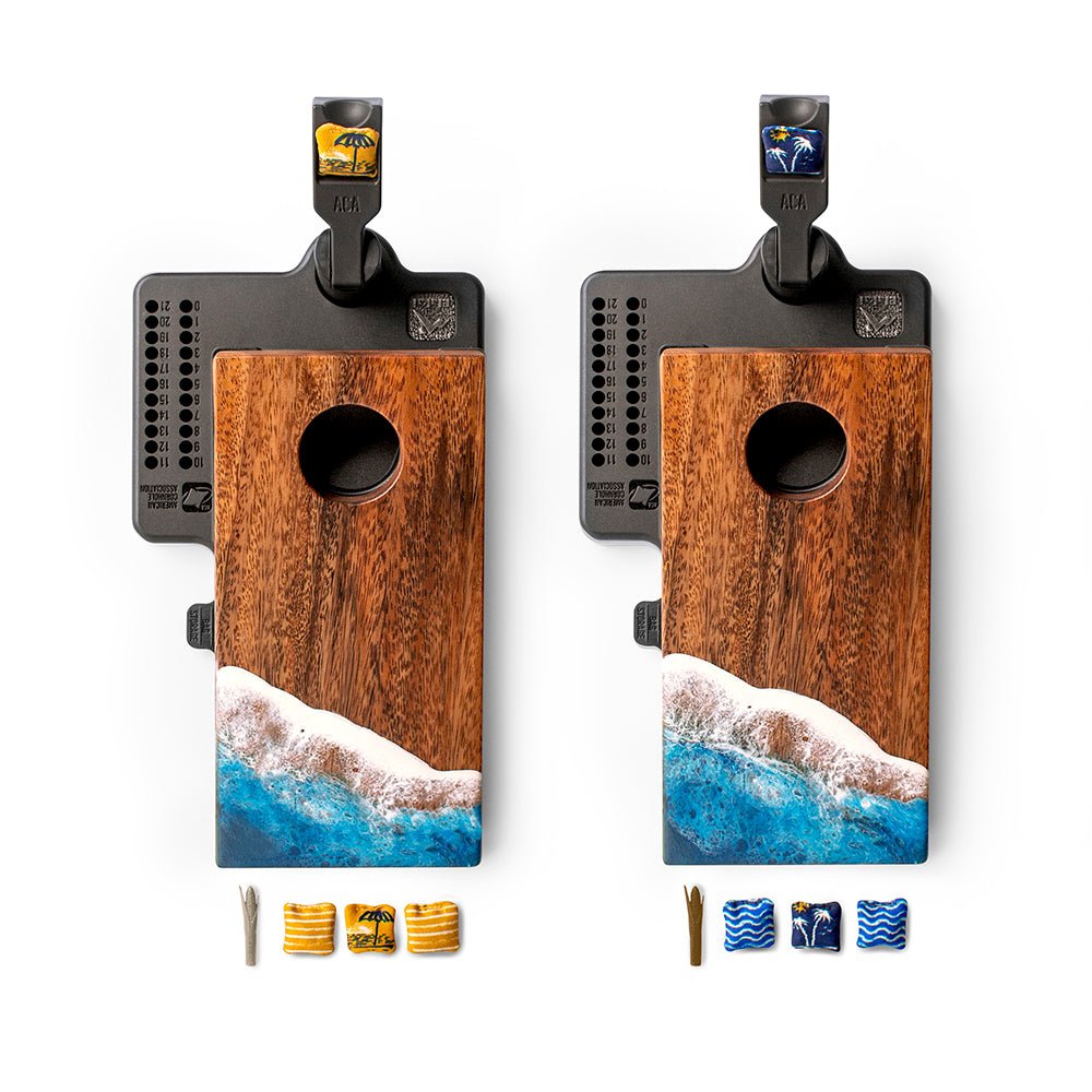Two wooden cornhole boards with ocean design and accessories on a white background