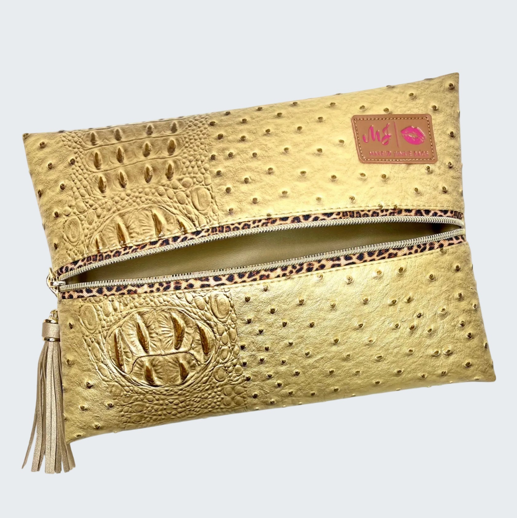 Gold clutch bag with embossed texture and tassel on a white background