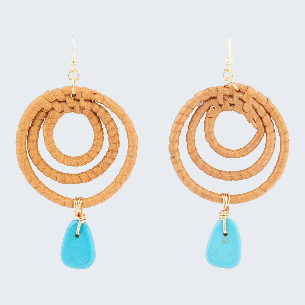 Pair of earrings with circular brown design and turquoise drops on a white background