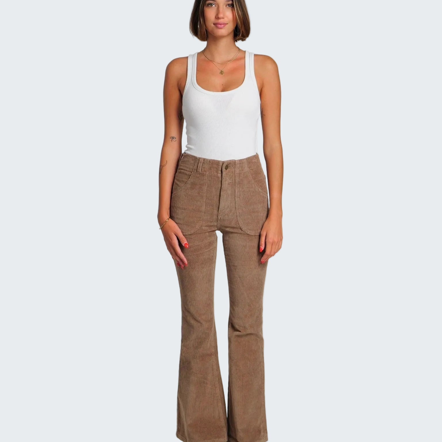 Woman wearing a white tank top and brown flared pants on a white background