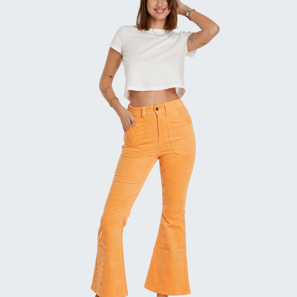 Woman wearing a white top and orange pants on a white background