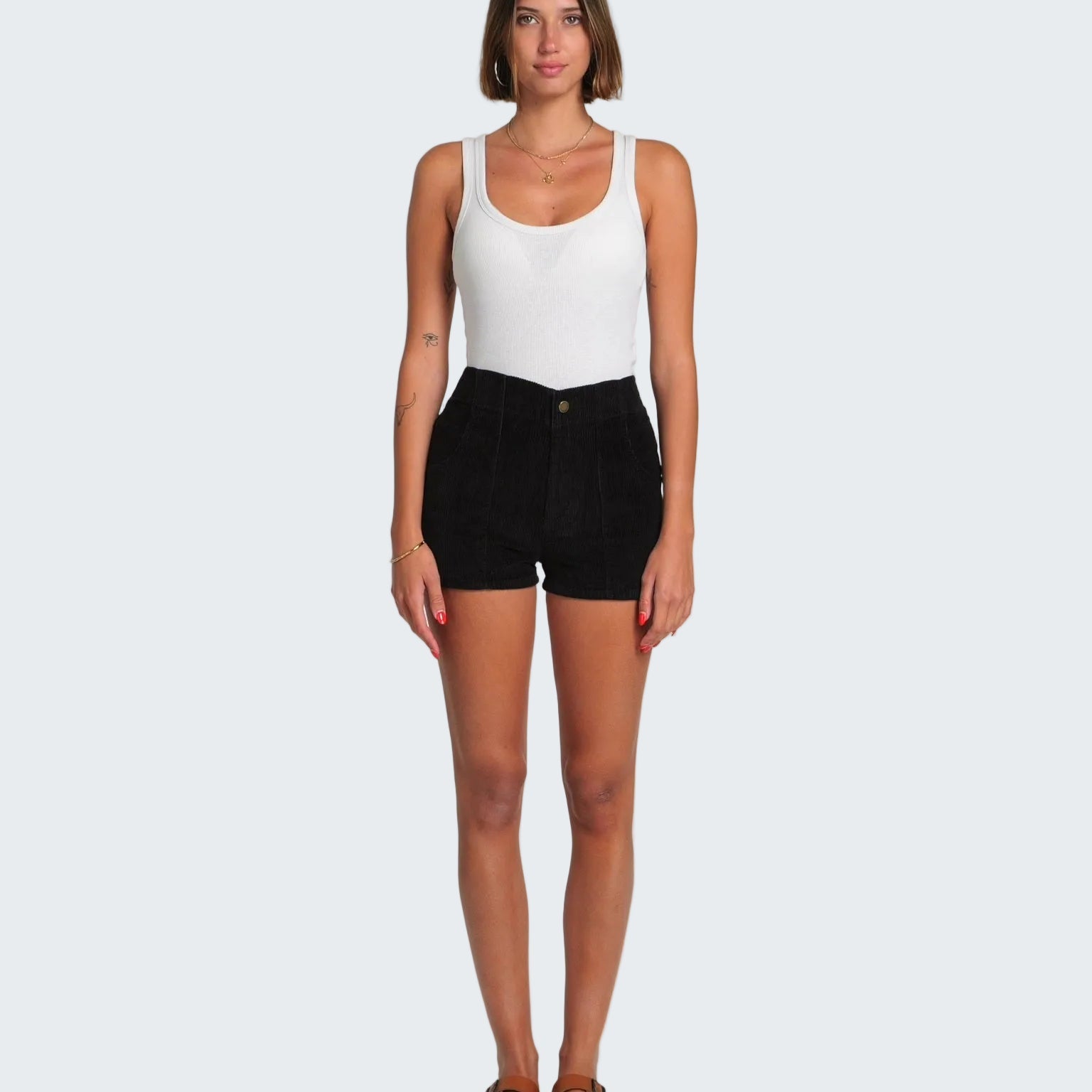 Woman wearing a white tank top and black shorts on a white background
