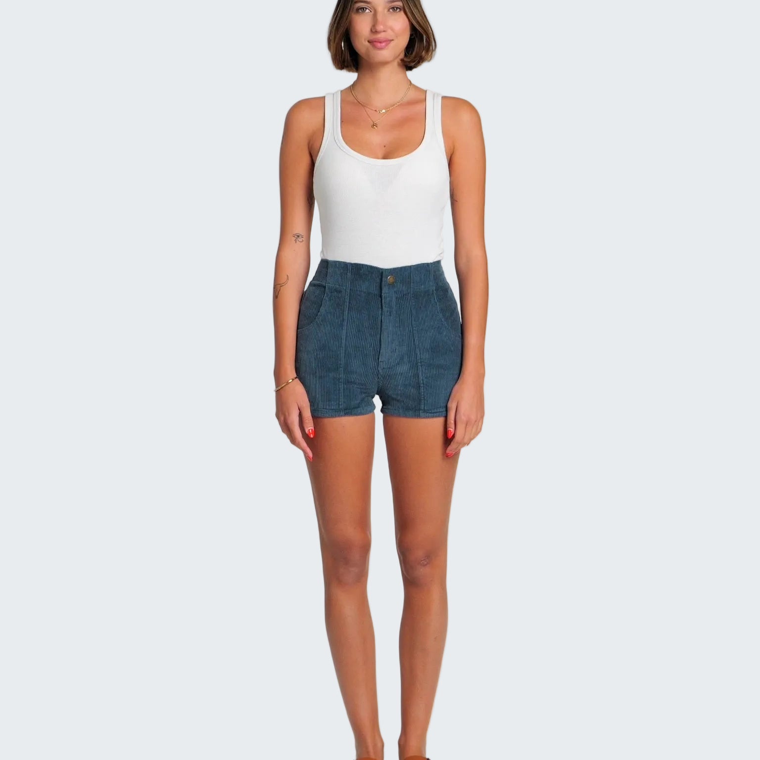 Woman wearing a white tank top and blue denim shorts on a white background
