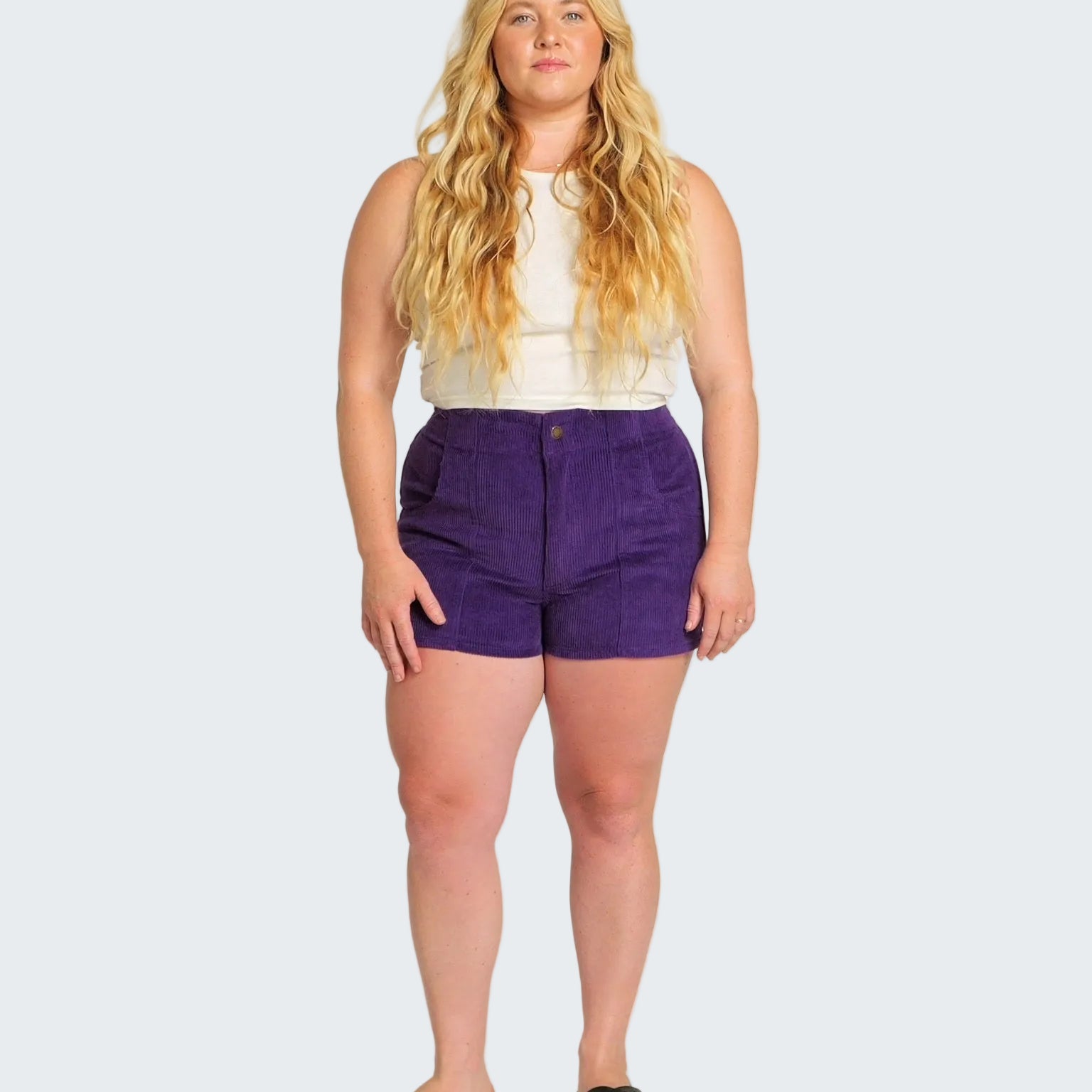 Woman wearing a white top and purple shorts on a white background