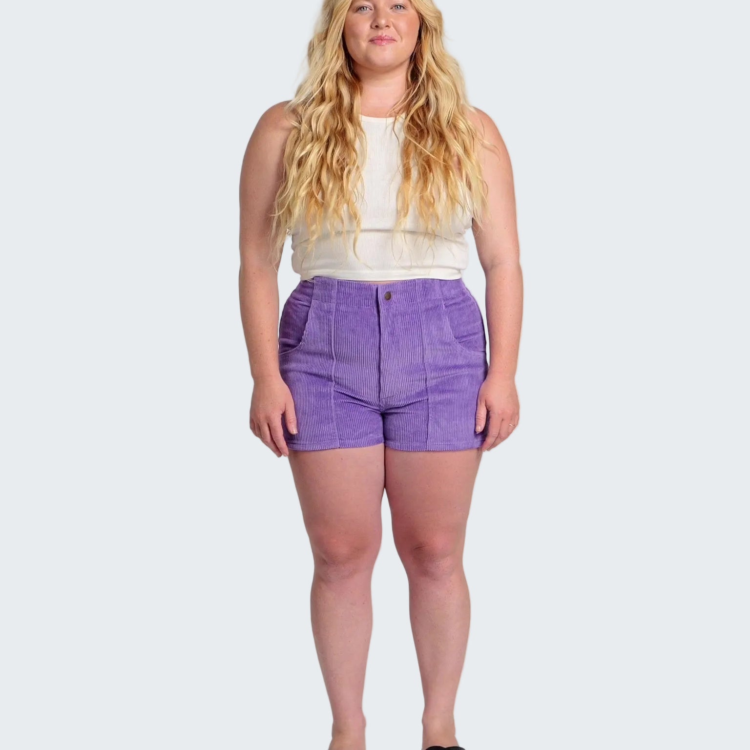 Woman wearing a white top and purple shorts on a white background