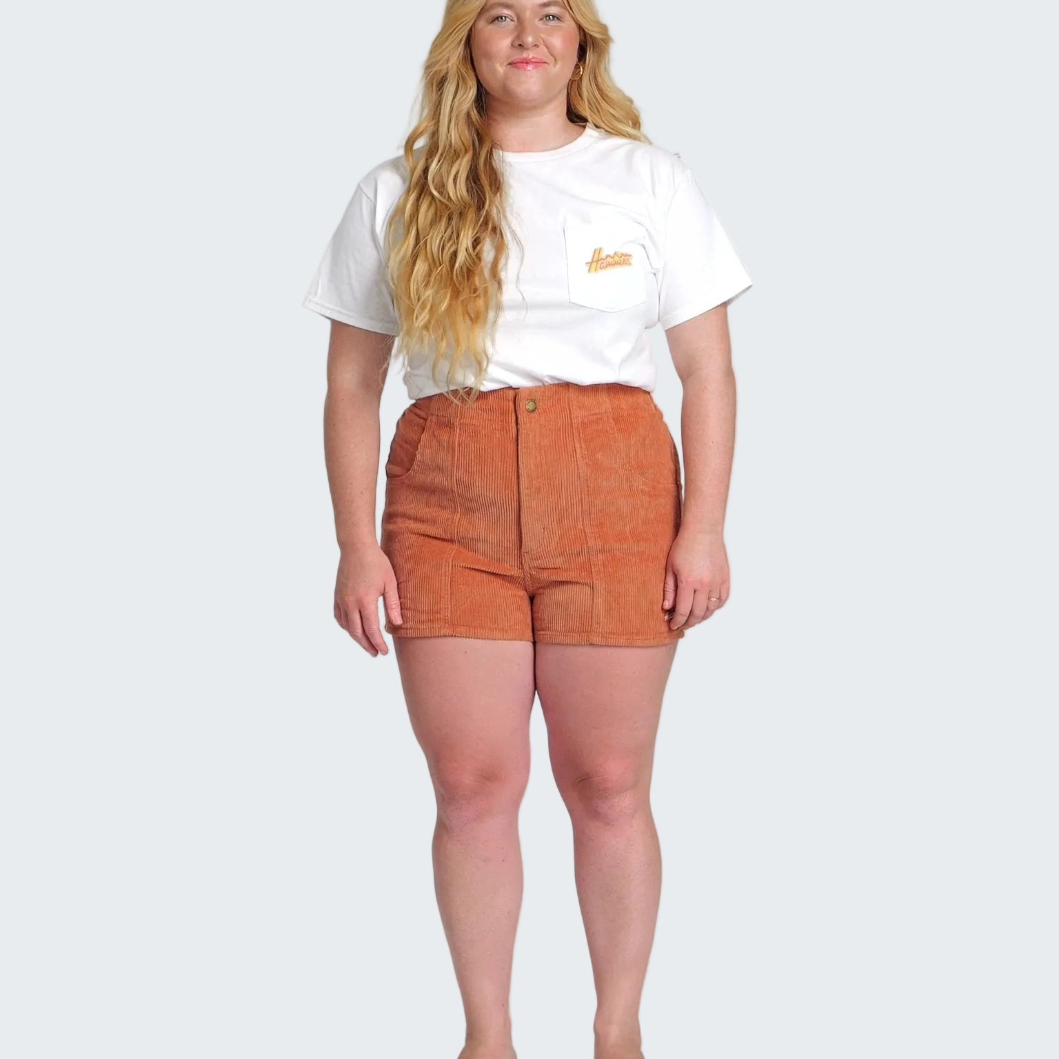 Person wearing a white t-shirt and orange shorts on a white background