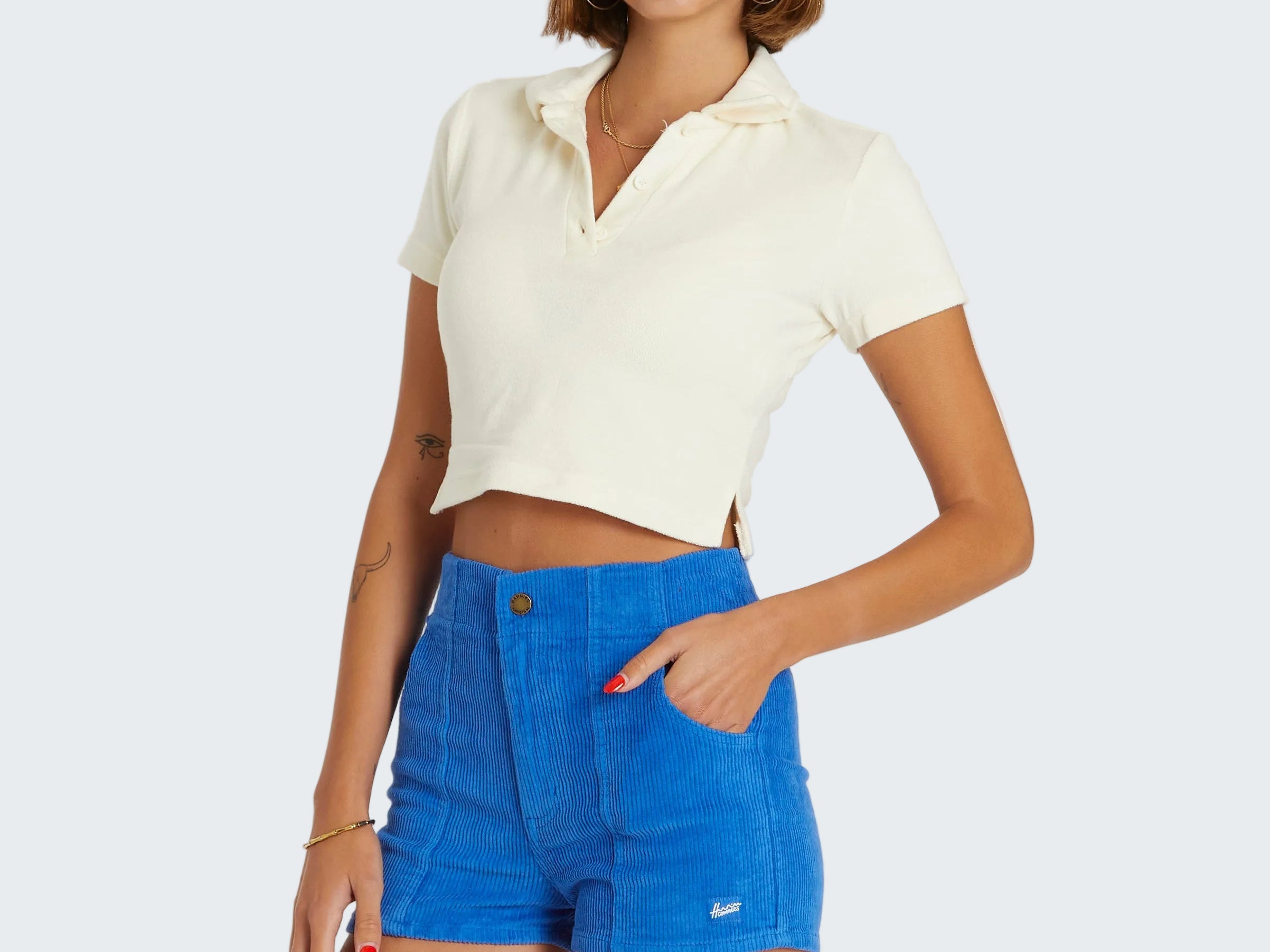 Woman wearing a white cropped top and blue shorts on a white background