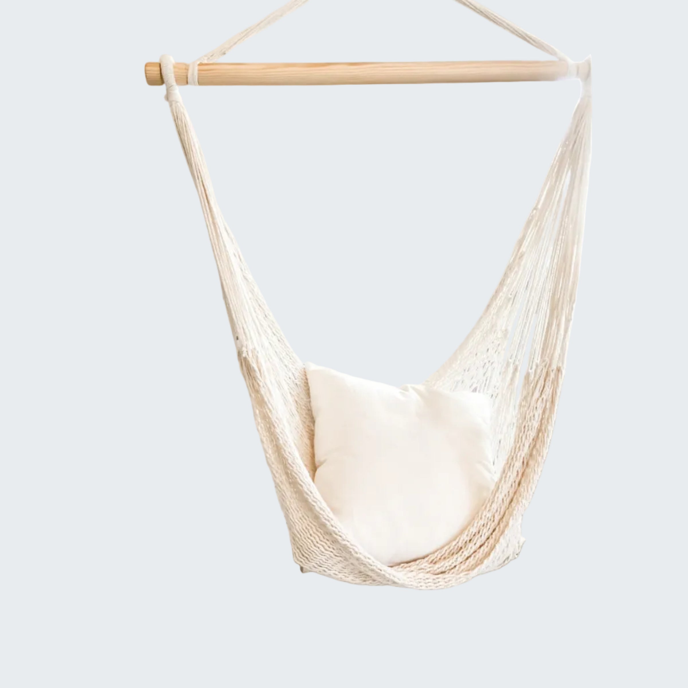Beige hammock chair with a white pillow in a room with decorative screen and plant.