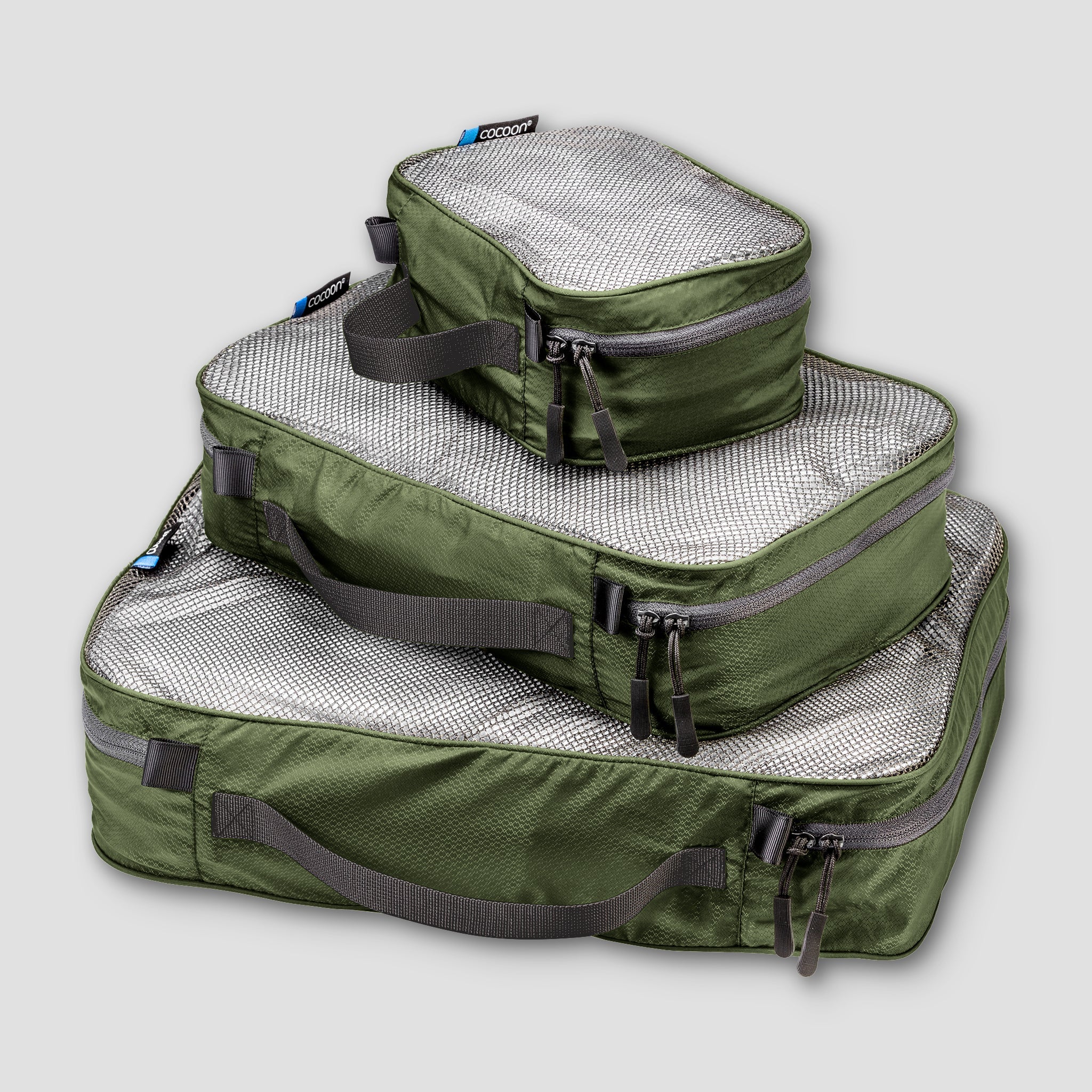 Set of green packing cubes with gray zippers on a light gray background