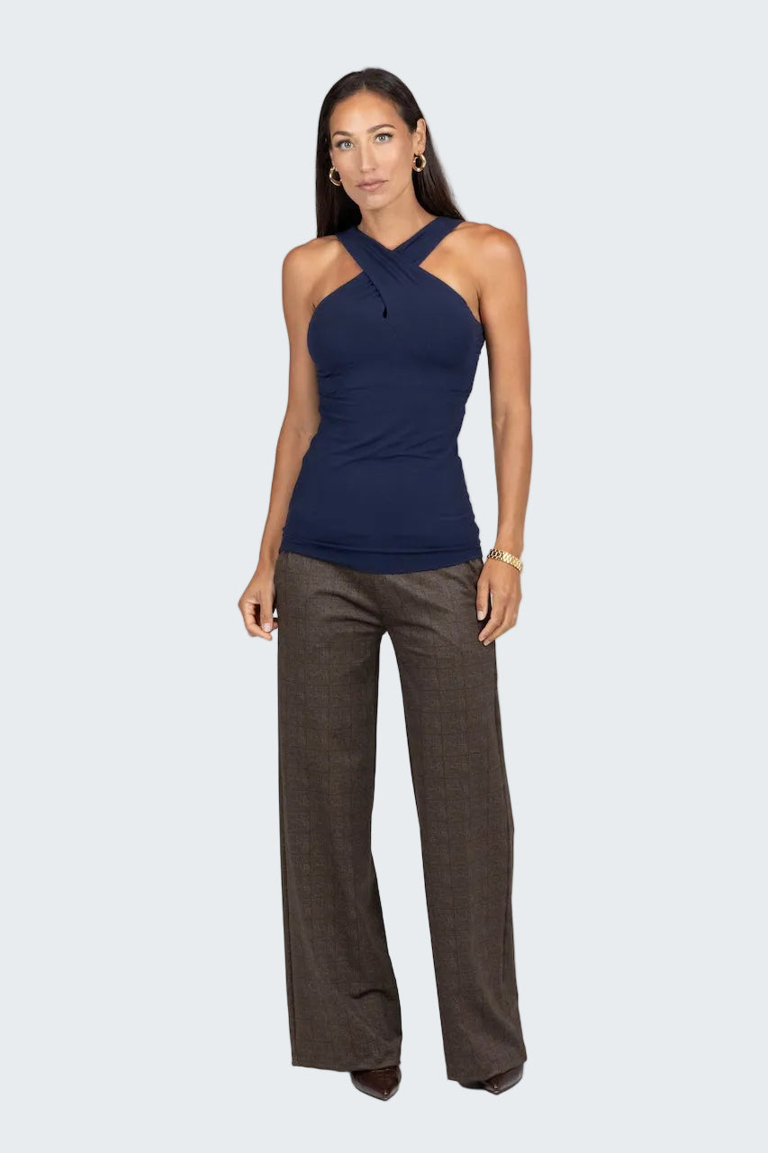 Woman wearing a navy halter top and brown pants on a gray background