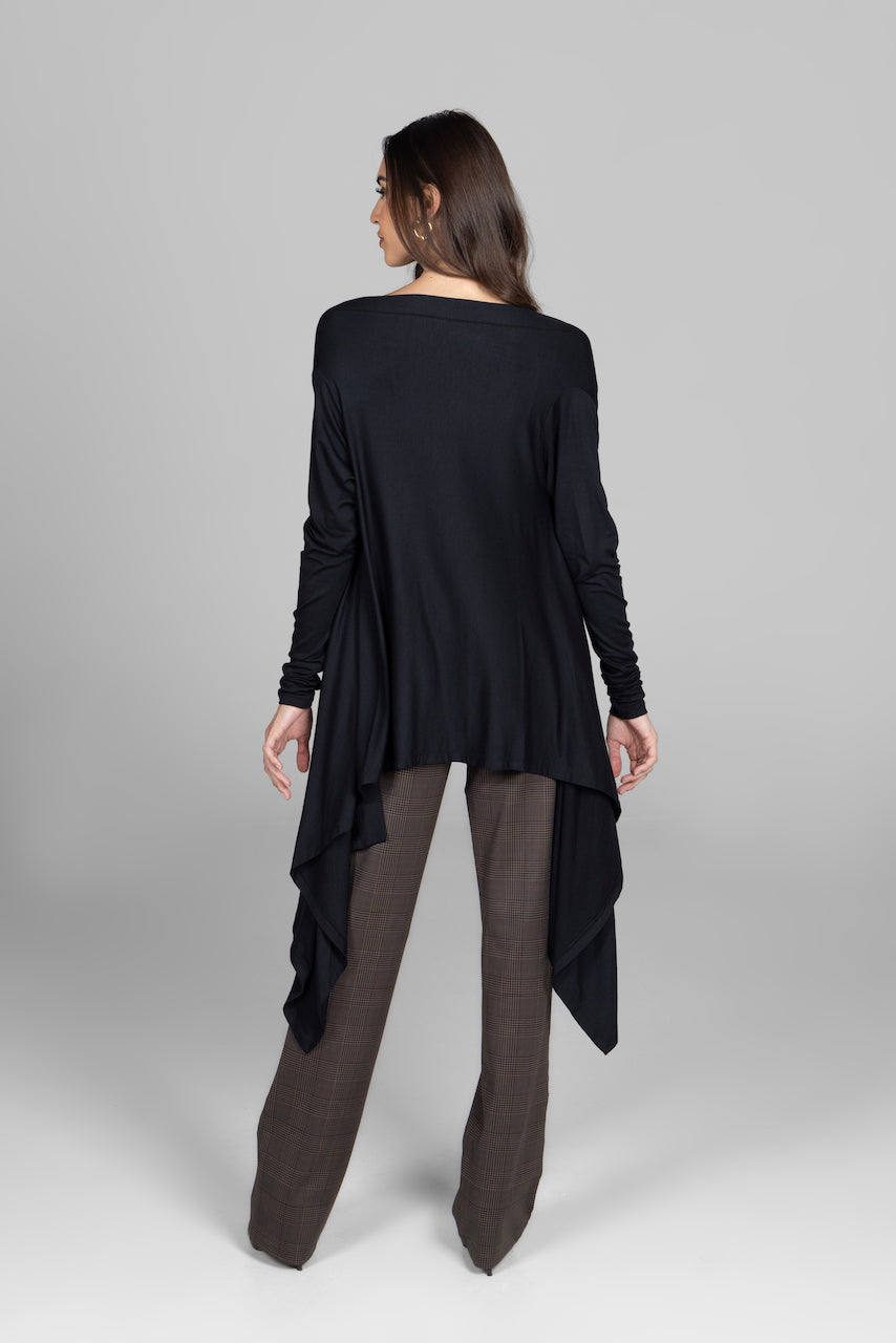 Woman wearing a black long-sleeve top and brown pants on a gray background