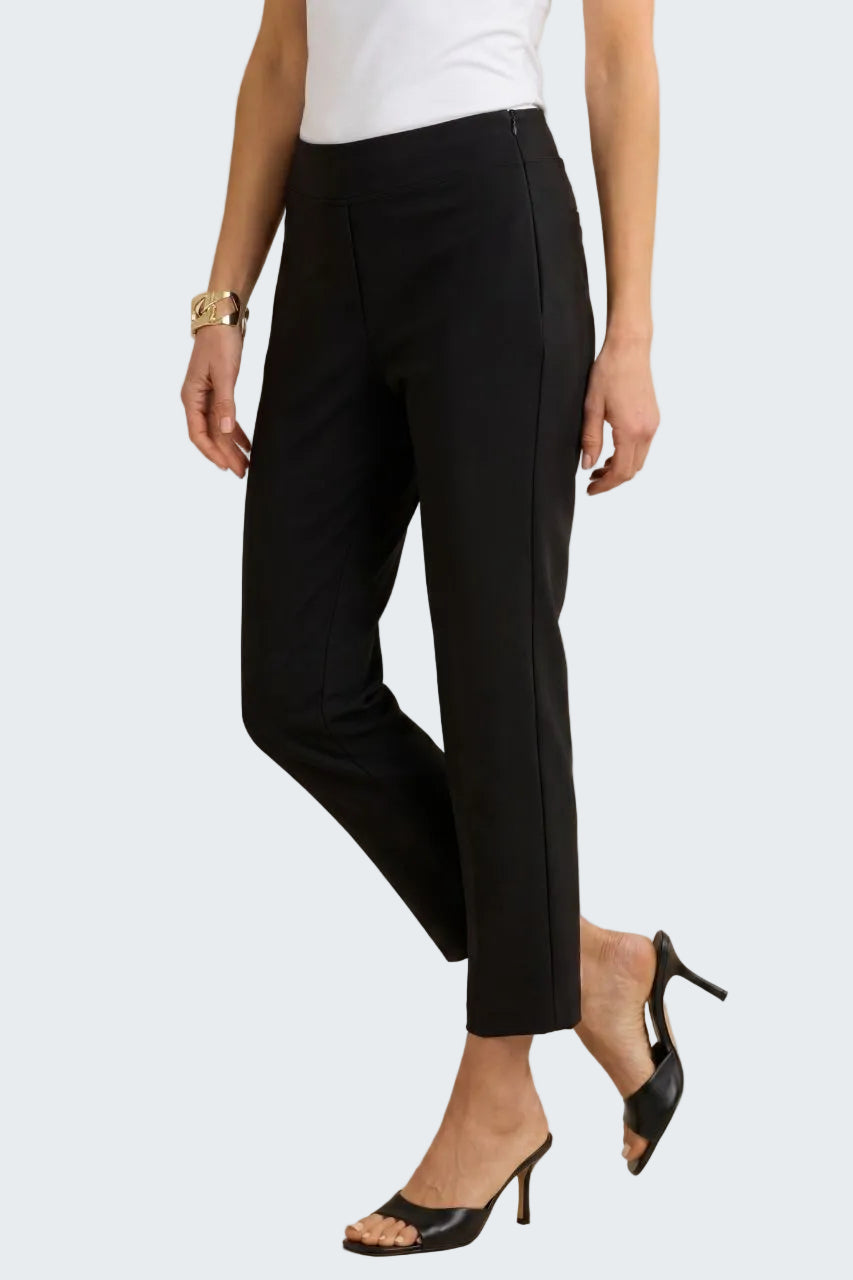 A model wearing black cropped ankle-length trousers with side seam detailing, paired with a white top and black mule heels, against a neutral beige background.
